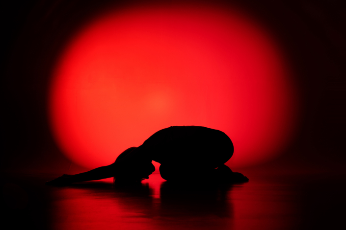 Joogakuva studiossa – lapsen lepoasento punaisella taustalla Studio yoga portrait in Child's Pose with a red background