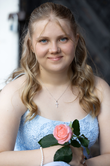 Rippikuvaus Rippikuva tytöstä vaaleansinisessä mekossa ruusun kanssa. Confirmation portrait of a girl in a light blue dress holding a pink rose.
